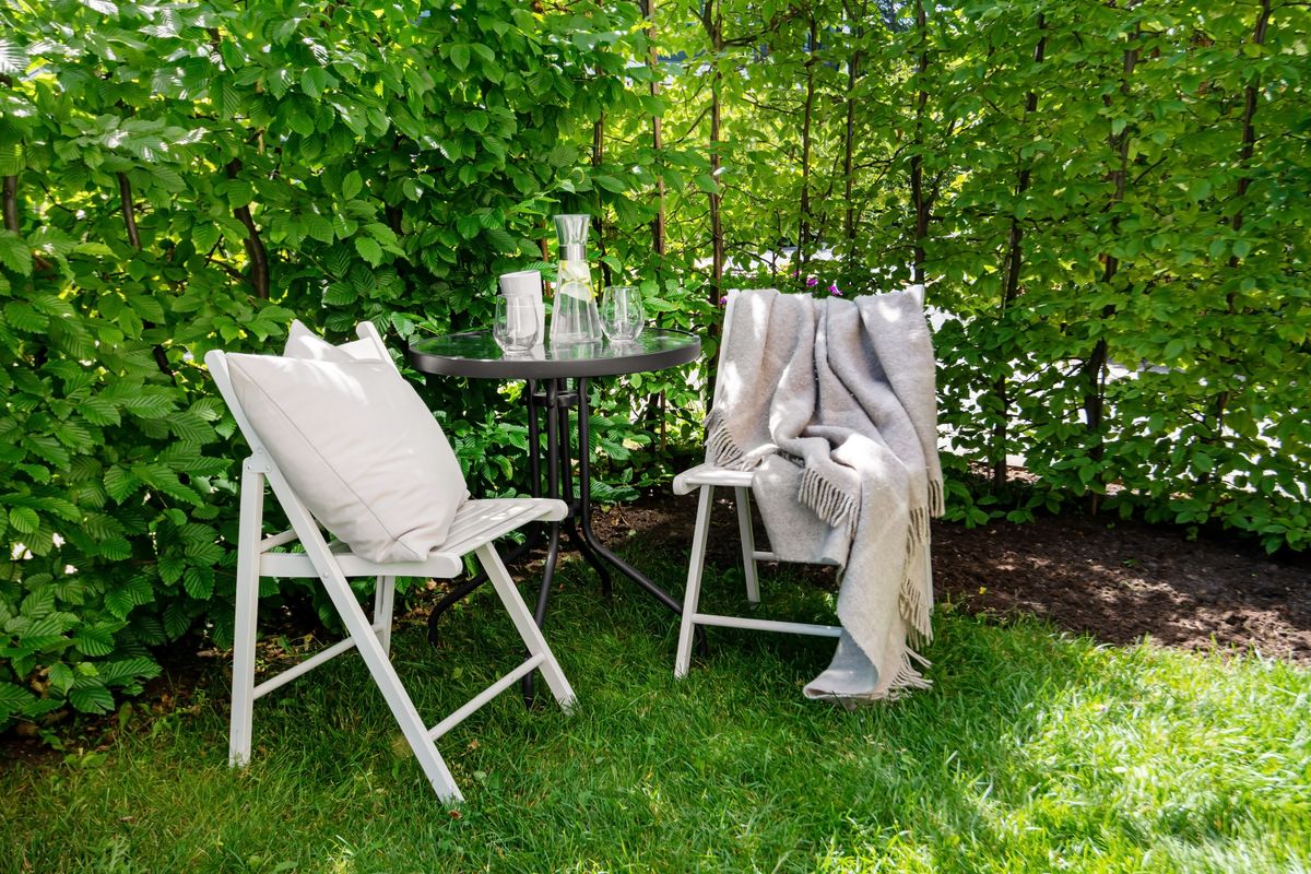 Two cushioned chairs and a table with refreshments on a green lawn